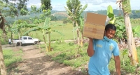 IN PHOTO: An instructional manager, one who is facilitating classes for the Alternative Learning System (ALS) in light mood, carrying a box of learning materials transported to the community learning center in a remote area in a camp community. ALS is a modified education program in the Philippines for those who was not or are not capable of studying due to poor access, services, poverty and war for some. 